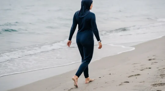 Femme en burkini marchant vers la mer sur une plage méditerranéenne