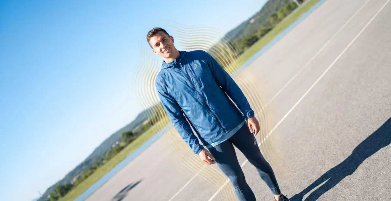 Athlète portant une veste réfrigérante bleue sous un soleil intense, symbolisant le confort thermique en période de canicule.